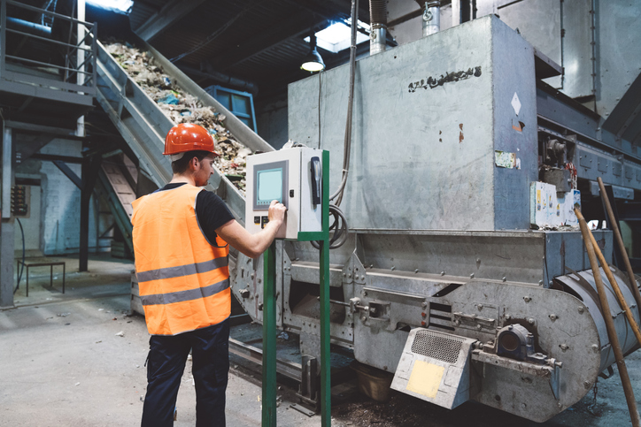 pracownik stoi przy maszynie do recyklingu